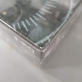 Close-up of a sealed Pandemic Legacy: Season 2 (Black) (Damaged) board game by Z-Man Games, showing its plastic wrap and graphic design with white lines and circles, plus a dented corner indicating slight damage.