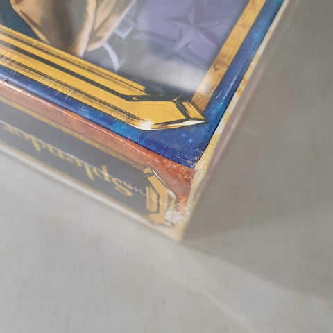 A close-up of a shrink-wrapped Splendor: Marvel (Damaged) box by Space Cowboys, with noticeable corner damage and frayed edges. The box showcases a blue, gold, and purple Avengers and Infinity Stones-inspired design.