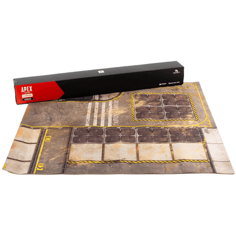 The Apex Legends: The Board Game – Playmat by Glass Cannon Unplugged features an industrial neoprene design with metal plates, yellow hazard lines, worn textures, and comes beside its black and red APEX-branded rectangular packaging.