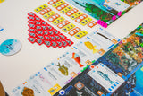 Finspan by Stonemaier Games is a colorful board game with fish-themed cards, red and orange tokens, pink markers, and a circular token on a white table. The vibrant board features underwater and ocean zones—ideal for aspiring marine researchers.