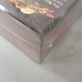 Close-up of HEXplore It: The Sands of Shurax (Damaged) by Mariucci J. Designs, showing shrink-wrap with a small tear and dent in one corner, revealing minor damage to the packaging.