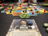 A close-up shows a character card labeled ODESSA with game pieces from Off the Page Games' Harrow County: The Game of Gothic Conflict, surrounded by colorful hexagonal tiles and tokens spread across the table.