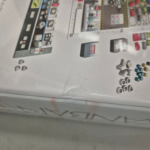 A close-up of the Kanban EV (Damaged) box by Eagle-Gryphon Games reveals part of the game board, tokens, dice, and cards with automobile and electric vehicle themes, plus a visible dent on one corner.