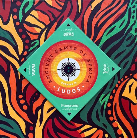 The Lemery Games box for Ludos: Ancient Games of Africa stands against a vibrant orange, red, green, and yellow patterned background, featuring a central circular design as part of the Ludos collection.