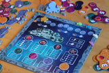 A close-up of Lumicora by Pegasus Spiele, a vibrant tile-laying game with marine pieces like coral, shells, and an octopus token set on a blue underwater-themed board with icons and scoring tracks.