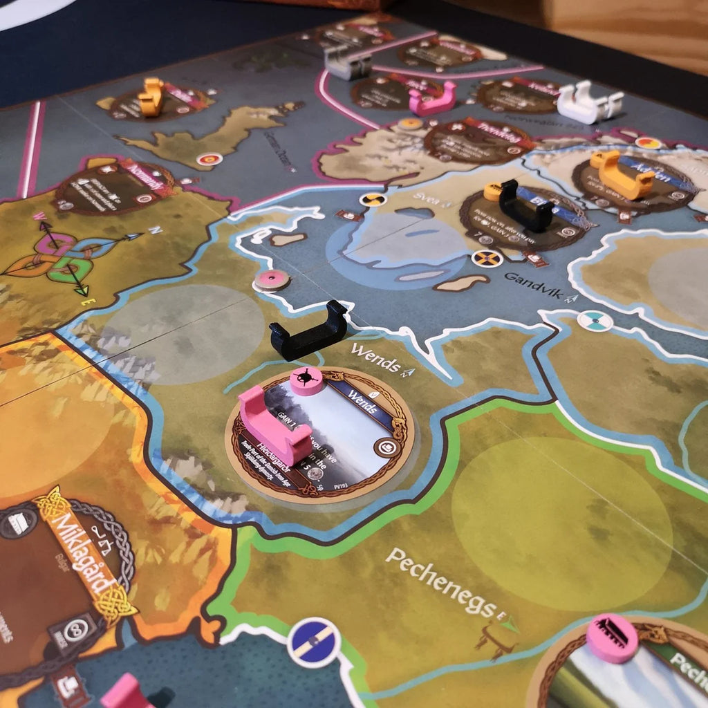 A close-up of Pax Viking by Ion Game Design shows regions, tokens, and black, white, and pink ships on the board. Territory names like Wends and Vikings appear alongside various icons and paths in this historical strategy game.