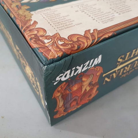 A close-up of the Tales of the Arthurian Knights (Damaged) board game box by WizKids, showing ornate King Arthur artwork and a visible logo, with a dent or crease on one corner.