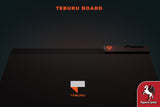 A dark image displays the Teburu Board by Pegasus Spiele, featuring its logo at the center, "TEBURU BOARD" at the top, and the Pegasus Spiele logo in the lower right, showcasing this innovative board game system with digital integration.