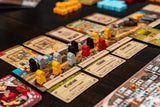 Colorful tokens in yellow, black, gray, and red are placed on cards with text and illustrations during gameplay of The Anarchy by Renegade Game Studios, highlighting dynamic medieval strategy action.