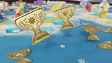 Wondrous Creatures: Upgraded Components Expansion by Bad Comet features hexagonal tiles, game pieces, and upgraded wooden and metal trophy icons for rewards, all set on a blue board background.