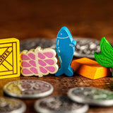 Enhance your Yokohama game with Synapses Games' Yokohama: Premium Tokens—a set of colorful wooden pieces shaped like a crate, fish, leaf, and cheese, plus silver coins—perfect for stylish board gaming!.
